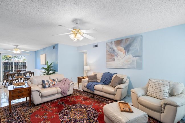 Living area with a textured ceiling, ceiling fan, and visible vents | Image 8