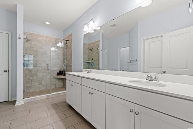 Master bathroom featuring a stall shower with glass doors, double vanity, and a walk in closet. | Image 14