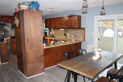 Kitchen with dark hardwood / wood-style flooring, backsplash, hanging light fixtures, and kitchen peninsula | Image 2