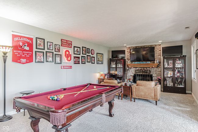 game room featuring carpet, a brick fireplace, and baseboards | Image 38