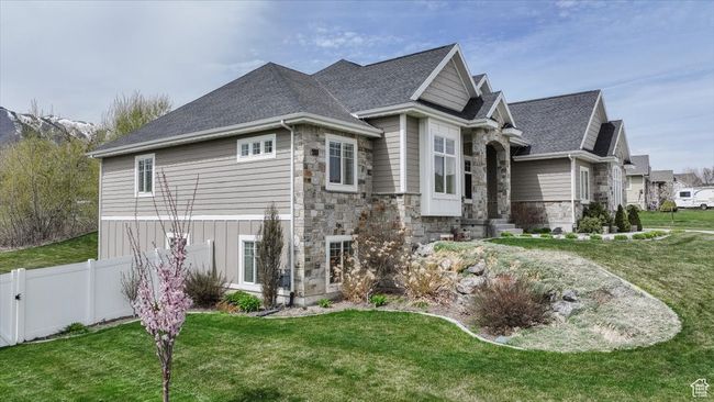 View of property exterior featuring a yard, roof with shingles, fence, and stone siding | Image 18