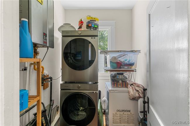 Laundry room featuring tankless water heater, stacked washer / dryer, and laundry area | Image 18