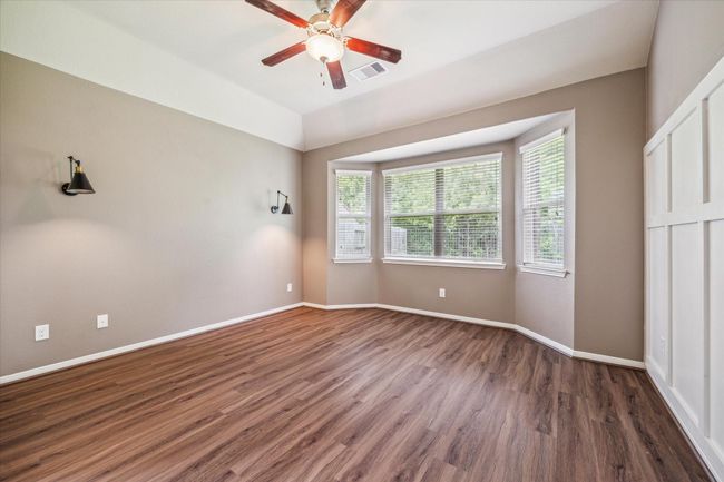 Elegant primary bedroom featuring exquisite wall molding, stylish sconces, and serene nature views. | Image 22