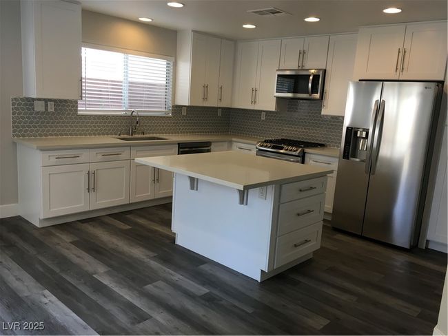 Kitchen with fridge, visible vents, range, and white cabinets | Image 7