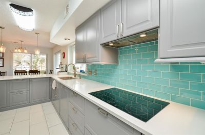 A gorgeous wall of brilliant aqua subway-style tile draws the eye and welcomes tasking in your newly remodeled/updated kitchen, featuring new stainless steel appliances, new induction cook top, great soft-close cabinetry everywhere, new quartz countertops and vibrant tile backsplash. | Image 2