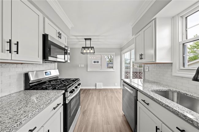 Kitchen featuring a sink, light wood-style floors, crown molding, baseboards, and appliances with stainless steel finishes | Image 16