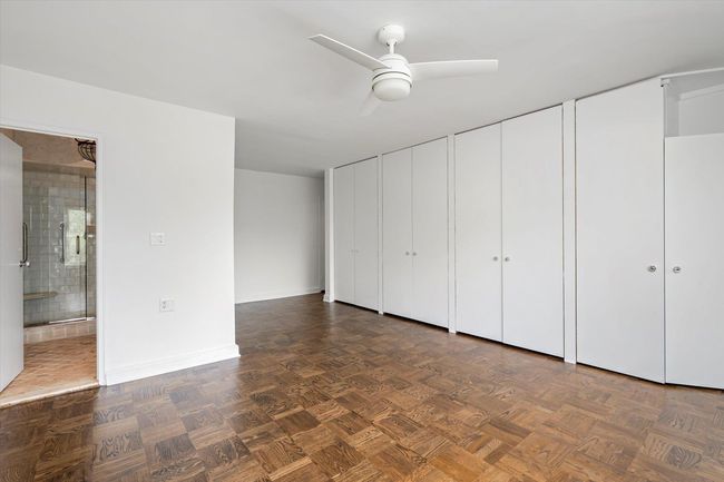 Unfurnished bedroom with two closets, baseboards, ensuite bath, and a ceiling fan | Image 14