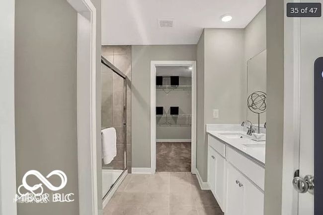 Primary full bath with a stall shower, tile patterned flooring, a sink, and a spacious closet | Image 16