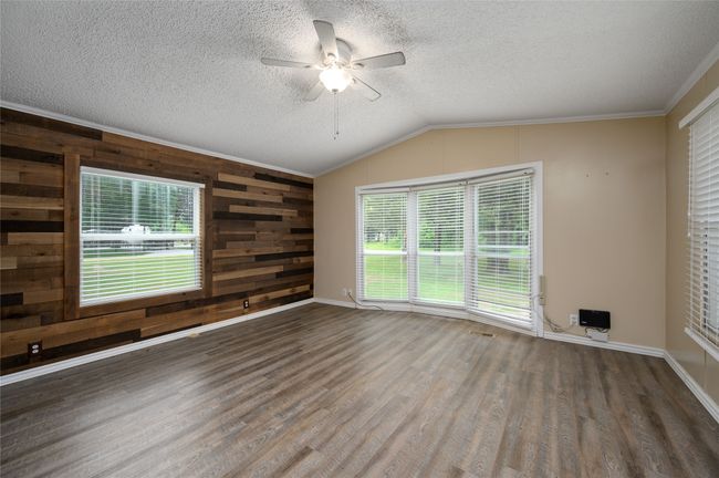 Empty room with wood finished floors, ceiling fan, a textured ceiling, plenty of natural light, and vaulted ceiling | Image 27