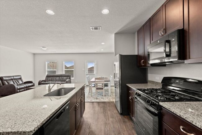 Kitchen featuring black appliances, a sink, open floor plan, dark wood-style flooring, and a textured ceiling | Image 14