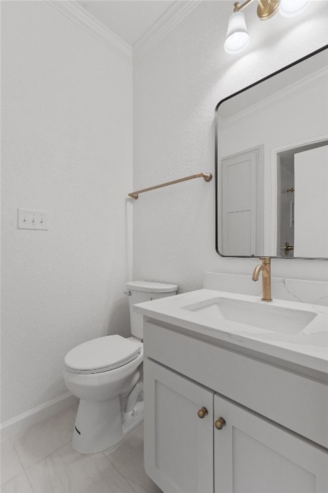 Bathroom featuring vanity, toilet, crown molding, and marble finish flooring | Image 25