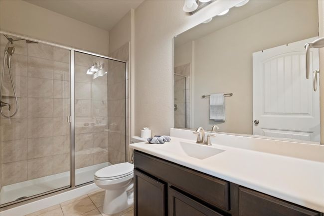 Bathroom with toilet, vanity, a shower stall, and tile patterned flooring | Image 34