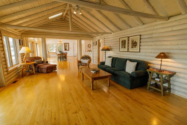 Living room with wooden ceiling, light wood-type flooring, rustic walls, and beamed ceiling | Image 32