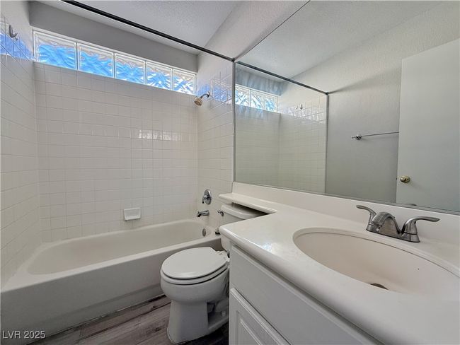 Bathroom with toilet, shower / bath combination, wood finished floors, a textured ceiling, and vanity | Image 39