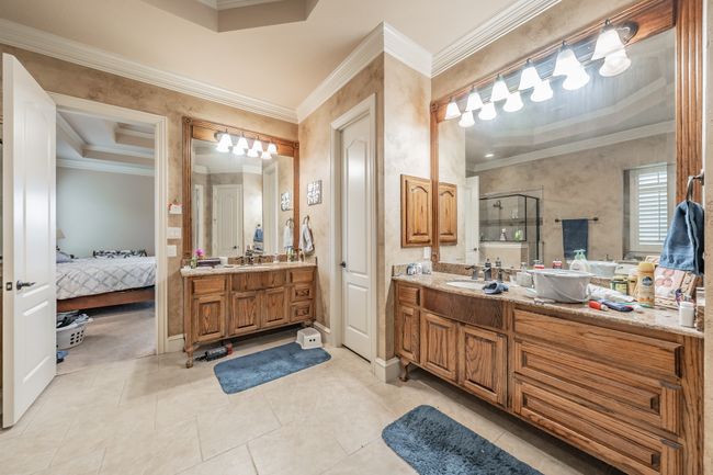 Bathroom with crown molding, ensuite bath, two vanities, a shower stall, and tile patterned floors | Image 25