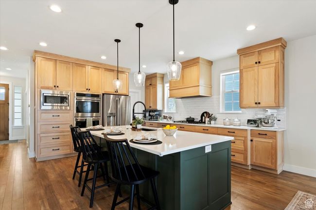 Kitchen with light brown cabinets, a sink, a breakfast bar, stainless steel appliances, and backsplash | Image 10