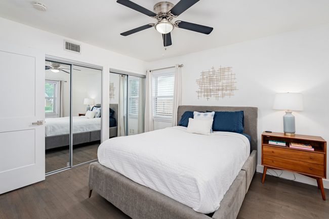 The primary bedroom has an ensuite bathroom, wood floors, & ceiling fan. | Image 17