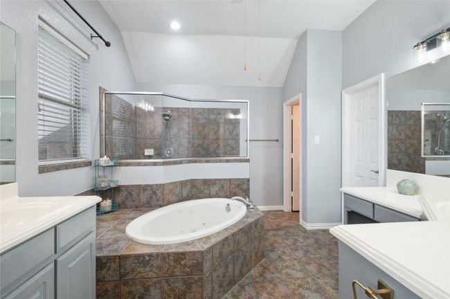 Full bath featuring a tub with jets, a tile shower, vaulted ceiling, and vanity | Image 23