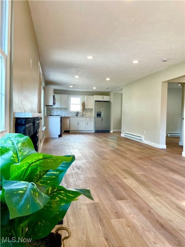 Living area with a baseboard radiator, light wood-style floors, recessed lighting, and a fireplace | Image 11