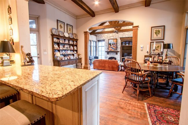 Kitchen featuring crown molding, ornate columns, beamed ceiling, light wood finished floors, and a peninsula | Image 7