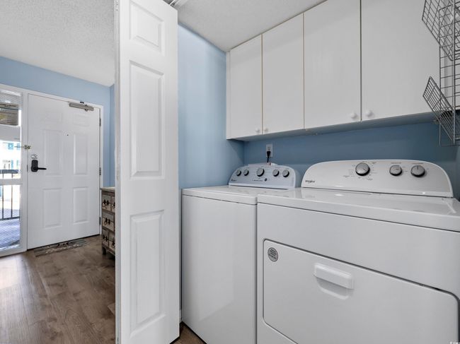 Clothes washing area with washer and dryer, cabinet space, a textured ceiling, and wood finished floors | Image 21