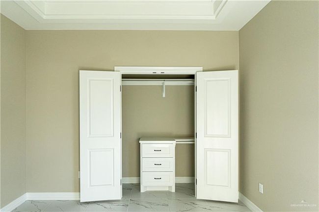 Unfurnished bedroom with marble finish floor, baseboards, and a closet | Image 6