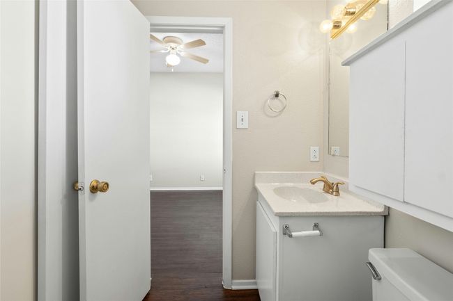 Bathroom with wood finished floors, ceiling fan, toilet, vanity, and baseboards | Image 20