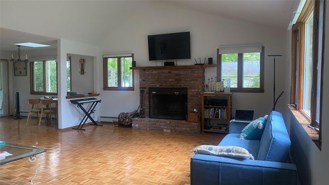 Living room with plenty of natural light, a brick fireplace, a skylight, and high vaulted ceiling | Image 9