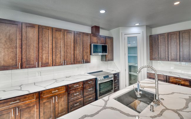 Kitchen with appliances with stainless steel finishes, light stone counters, sink, and backsplash | Image 28