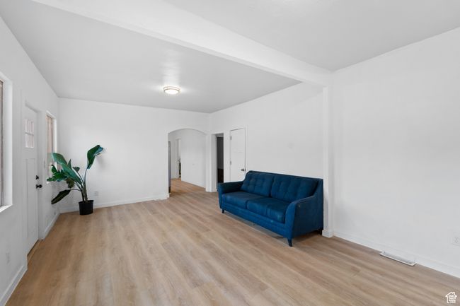Living area with arched walkways, visible vents, baseboards, and light wood-type flooring | Image 8