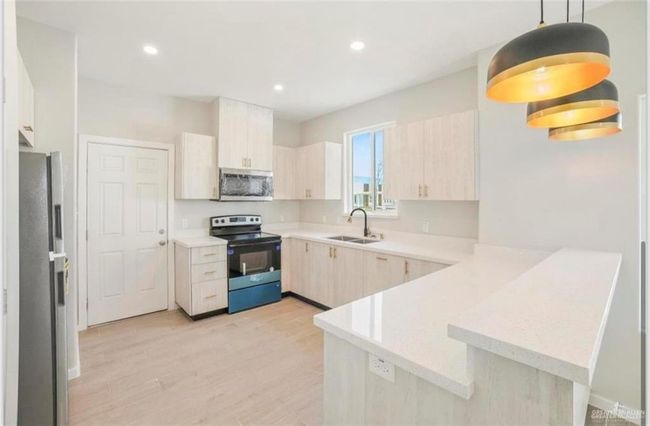 Kitchen featuring appliances with stainless steel finishes, light wood-type flooring, kitchen peninsula, pendant lighting, and light brown cabinets | Image 4