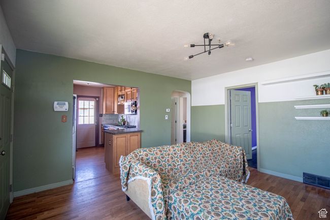 Bedroom with arched walkways, wood finished floors, baseboards, and visible vents | Image 10
