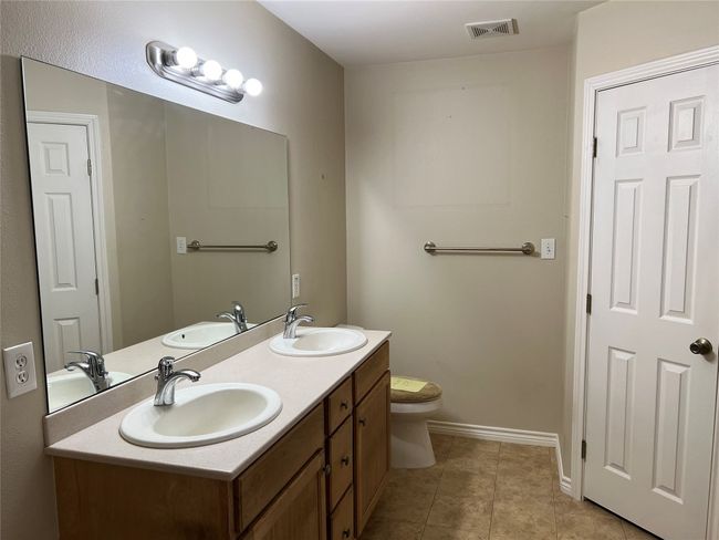 Bathroom with baseboards, toilet, tile patterned floors, and double vanity | Image 15