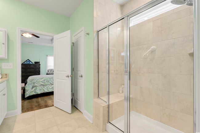 Bathroom with ceiling fan, tile patterned floors, a shower with door, and vanity | Image 24