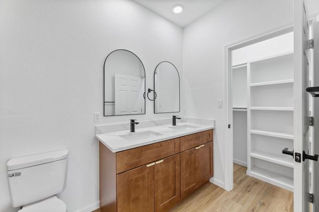 Full bathroom with double vanity, a sink, toilet, and closet with built ins | Image 16