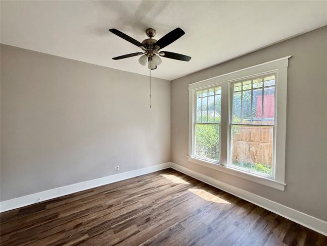Empty room with dark wood finished floors and a ceiling fan | Image 10