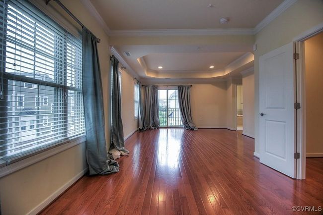 Unfurnished room with wood finished floors, baseboards, a smoke detector, ornamental molding, and a tray ceiling | Image 6