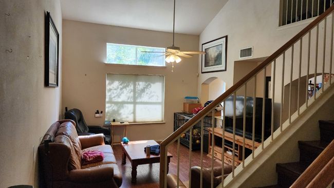 Living room with a towering ceiling, wood finished floors, stairs, and ceiling fan | Image 8