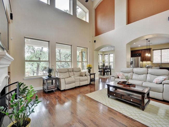 Living area with arched walkways, wood-type flooring, a high ceiling, and baseboards | Image 4