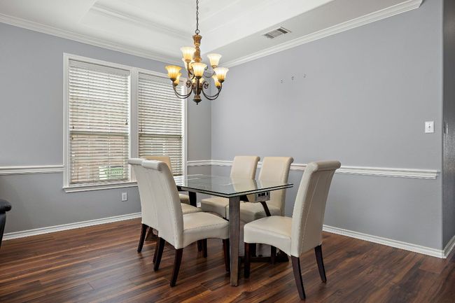 Dining area featuring a chandelier, dark wood-style flooring, ornamental molding, and baseboards | Image 6