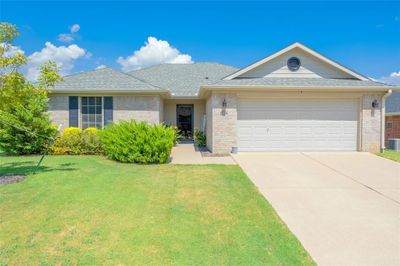 Ranch-style home with a garage, a front yard, and central air condition unit | Image 1