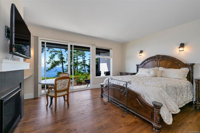 Bedroom featuring a fireplace, access to outside, and dark wood-style flooring | Image 52