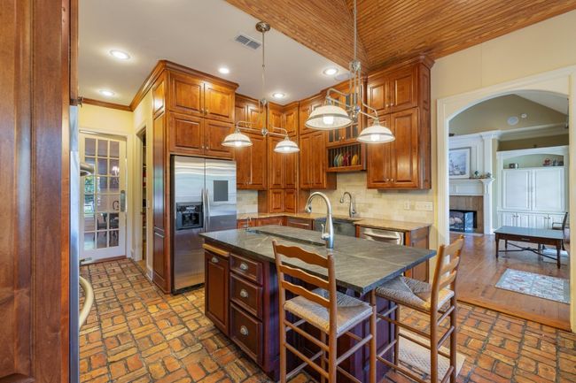 Kitchen with a tile fireplace, brick floor, stainless steel appliances, and visible vents | Image 21