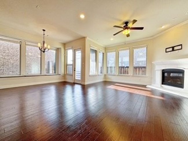 Unfurnished living room with a glass covered fireplace, a chandelier, wood finished floors, a ceiling fan, and recessed lighting | Image 8