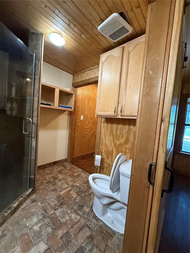 Full bath with toilet, a stall shower, wooden ceiling, and baseboards | Image 15