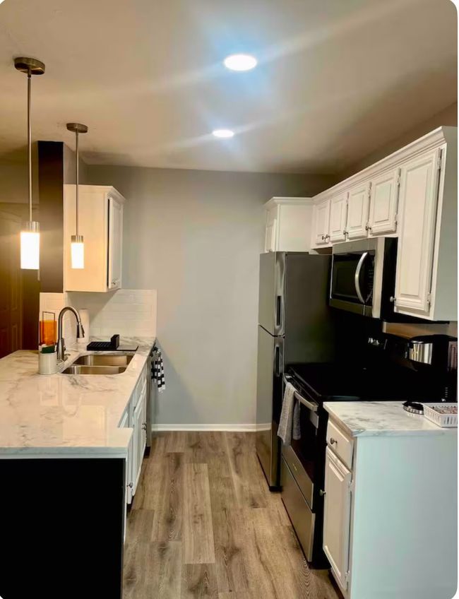 Kitchen featuring white cabinets, sink, decorative light fixtures, light hardwood / wood-style floors, and stainless steel appliances | Image 9