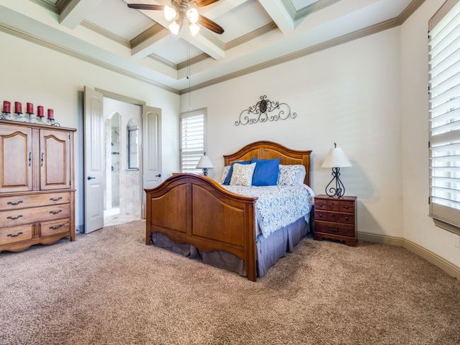 Primary bedroom featuring plush carpet, coffered ceiling and ensuite primary bathroom. | Image 13