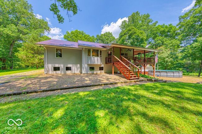 rear view of property with stairway, a lawn, an outdoor pool, a patio area, and a metal roof | Image 62