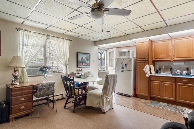 Dining space with ceiling fan, a baseboard heating unit, a drop ceiling, and light tile patterned floors | Image 19