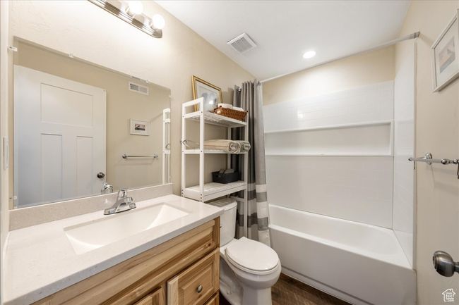 Full bath featuring toilet, shower / bath combo with shower curtain, vanity, and visible vents | Image 49